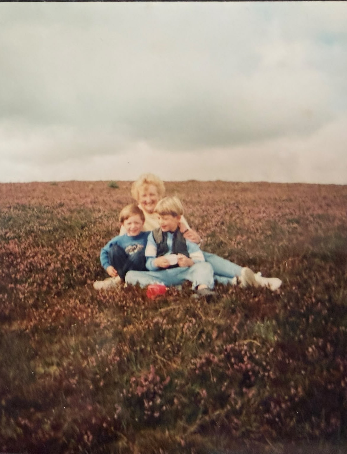 Nana Marlene sitting in a field with two of her grandchildren